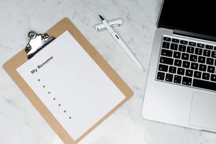 A blank resume on a desk next to a laptop